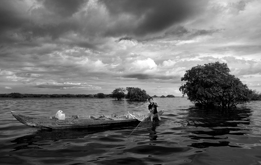 A young boy is on the hunt for fish on one of the world's largest and most beautiful of lakes- the Tonle Sap. 